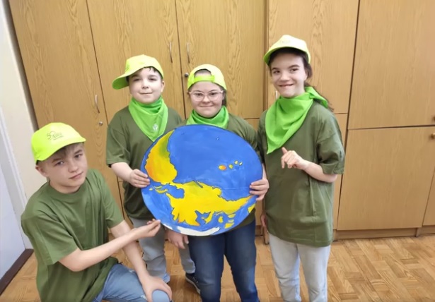 Grupa dzieci trzyma rysunek kuli ziemskiej